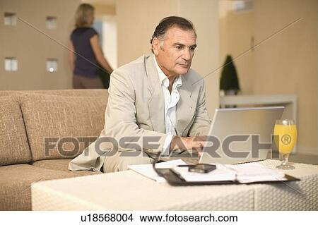 Picture - Businessman working on couch. Fotosearch
