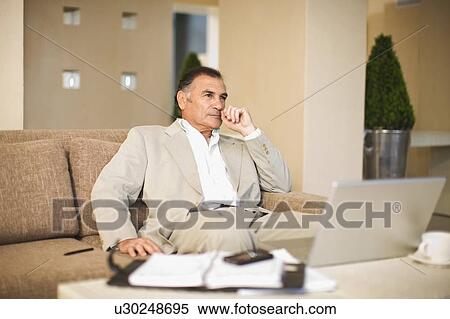 Businessman working on couch View Large Photo Image Stock Photography - Businessman working on couch. Fotosearch