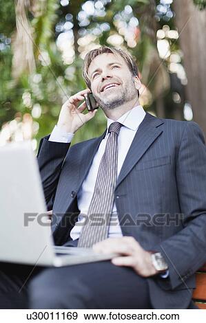 Stock Photo - Businessman working on laptop in park. Fotosearch