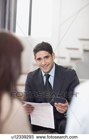 Stock Image - Businessman working with couple. Fotosearch