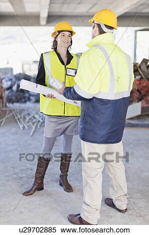 Stock Photography - Businesswoman and worker talking on site. Fotosearch