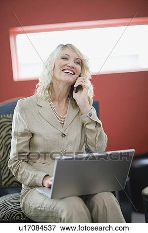 Stock Photo - Businesswoman on phone using laptop. Fotosearch