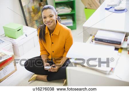 Stock Photo - Businesswoman using cell phone in office. Fotosearch