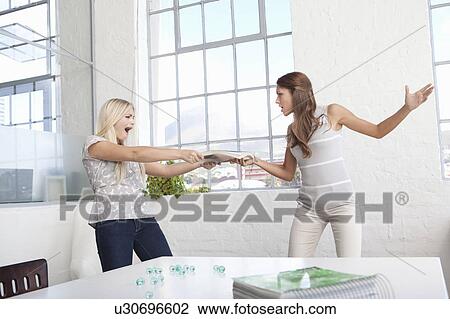 Stock Image - Businesswomen fighting over papers. Fotosearch