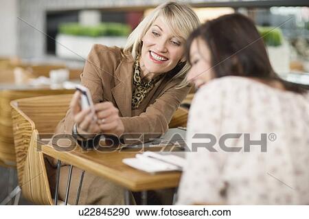 Stock Image - Businesswomen looking at cell phone. Fotosearch
