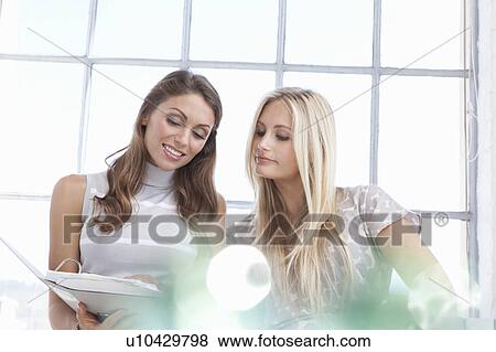 Businesswomen reading binder together View Large Photo Image Stock Photo - Businesswomen reading binder together. Fotosearch