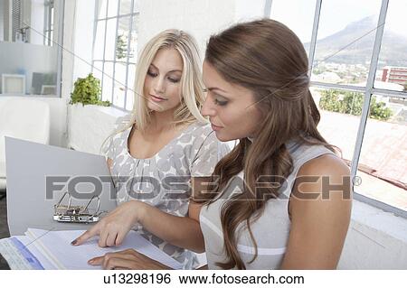 Businesswomen reading binder together View Large Photo Image Stock Photograph - Businesswomen reading binder together. Fotosearch