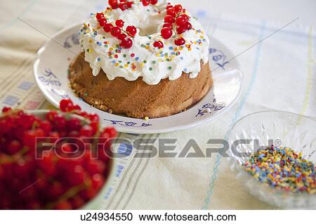 Stock Image - Cake, sprinkles and berries on table. Fotosearch