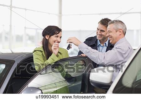 Stock Image - Car salesman giving keys to customer. Fotosearch