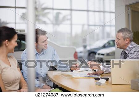 Car salesman giving papers to couple View Large Photo Image Stock Photo - Car salesman giving papers to couple. Fotosearch