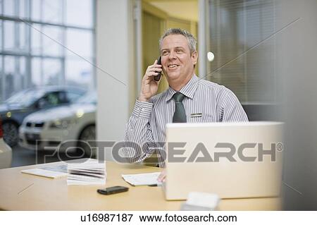 Car salesman on phone in showroom View Large Photo Image Stock Photo - Car salesman on phone in showroom. Fotosearch