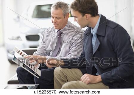 Stock Image - Car salesman talking with customer. Fotosearch