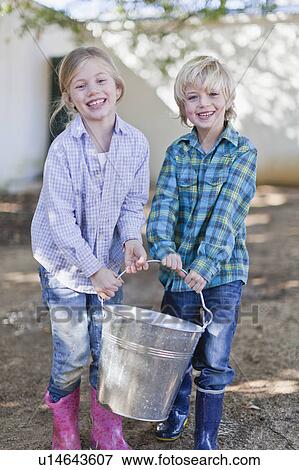 Children carrying heavy pail outdoors View Large Photo Image Stock Photo - Children carrying heavy pail outdoors. Fotosearch