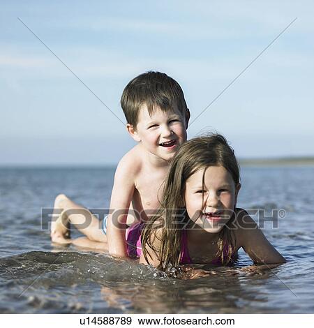 Stock Photo - Children playing in waves on beach. Fotosearch