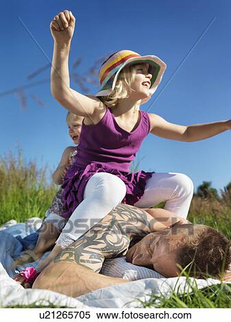 Stock Photography - Children sitting on father outdoors. Fotosearch