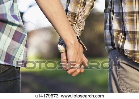 Stock Image - Close up of couple holding hands. Fotosearch