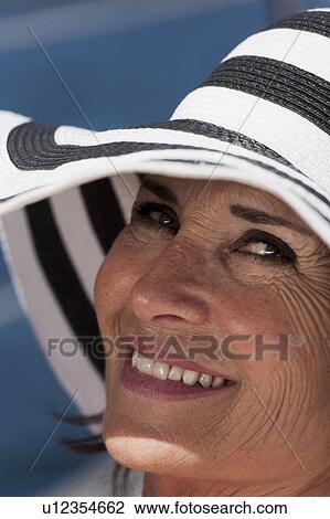 Stock Image - Close up of older woman wearing sunhat. Fotosearch