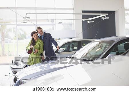 Couple admiring car in showroom View Large Photo Image Stock Photography - Couple admiring car in showroom. Fotosearch