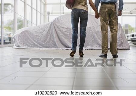 Couple admiring new car under cloth View Large Photo Image Stock Image - Couple admiring new car under cloth. Fotosearch