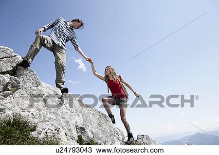 Couple climbing rocky hillside View Large Photo Image Stock Image - Couple climbing rocky hillside. Fotosearch