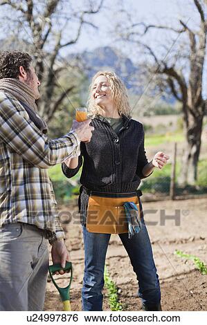 Stock Photograph - Couple drinking juice and gardening. Fotosearch