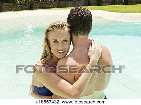 Stock Image - Couple hugging in swimming pool. Fotosearch