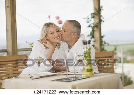 Stock Image - Couple in bathrobes kissing at breakfast. Fotosearch