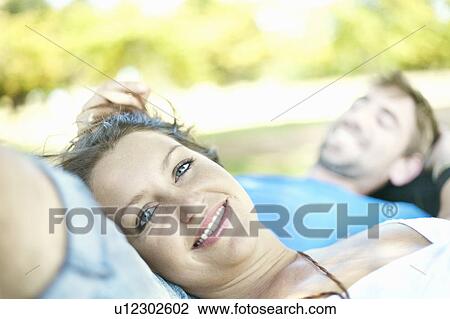 Stock Image - Couple laying in grass together. Fotosearch