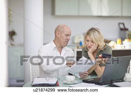 Couple paying their bills at home View Large Photo Image Stock Photo - Couple paying their bills at home. Fotosearch