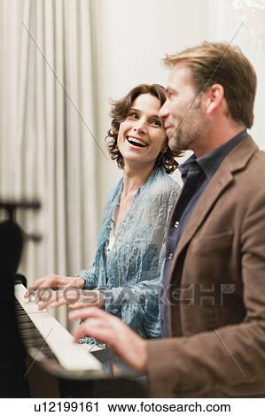 Couple playing piano together at home View Large Photo Image Stock Image - Couple playing piano together at home. Fotosearch
