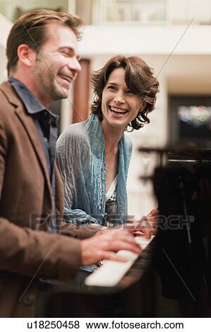 Stock Photo - Couple playing piano together at home. Fotosearch