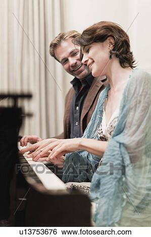Couple playing piano together at home View Large Photo Image Stock Photograph - Couple playing piano together at home. Fotosearch