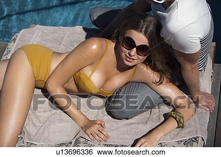 Stock Photograph - Couple relaxing by swimming pool. Fotosearch