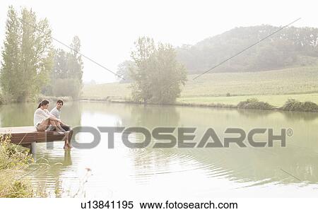 Couple relaxing on dock in lake View Large Photo Image Stock Photography - Couple relaxing on dock in lake. Fotosearch