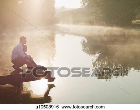 Couple relaxing on dock of lake View Large Photo Image Stock Photograph - Couple relaxing on dock of lake. Fotosearch