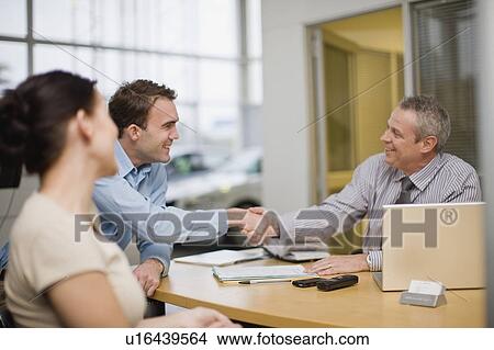 Picture - Couple shaking hands with car salesman. Fotosearch