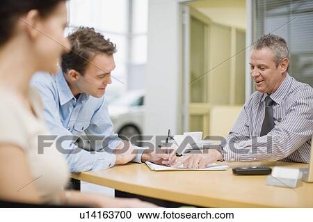 Couple signing papers with car salesman View Large Photo Image Stock Image - Couple signing papers with car salesman. Fotosearch
