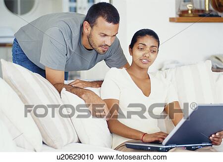 Couple using laptop in living room View Large Photo Image Stock Image - Couple using laptop in living room. Fotosearch