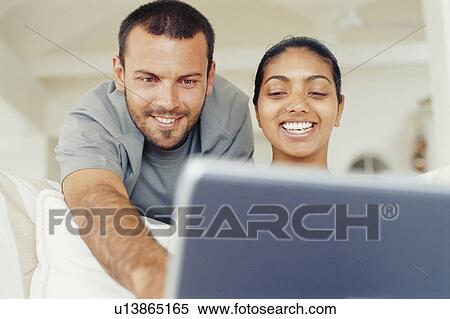Stock Photography - Couple using laptop in living room. Fotosearch