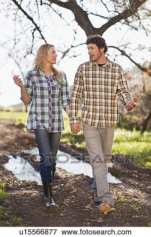 Couple walking hand-in-hand on dirt path View Large Photo Image Stock Photo - Couple walking hand-in-hand on dirt path. Fotosearch