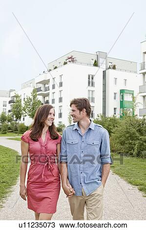 Stock Image - Couple walking hand-in-hand outdoors. Fotosearch