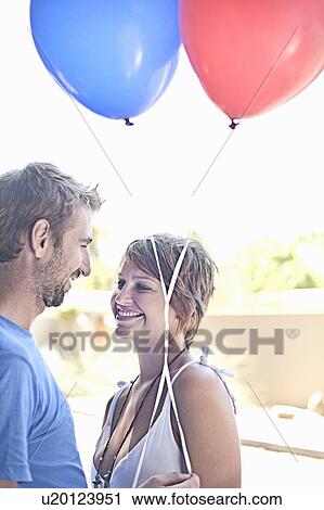 Couple with balloons smiling outdoors View Large Photo Image Stock Image - Couple with balloons smiling outdoors. Fotosearch