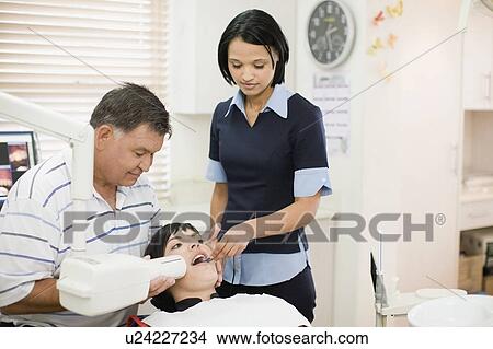 Picture - Dentist and assistant working on woman . Fotosearch