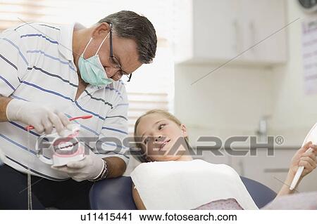 Stock Image - Dentist talking with girl in office. Fotosearch