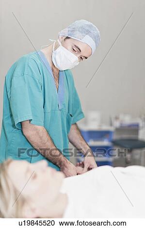 Stock Image - Doctor preparing patient for surgery. Fotosearch
