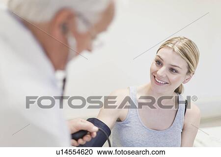 Stock Image - Doctor taking patient’s blood pressure. Fotosearch