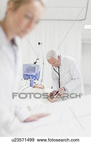 Doctor tending to patient in hospital View Large Photo Image Stock Photo - Doctor tending to patient in hospital. Fotosearch