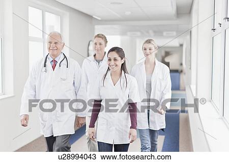 Stock Image - Doctors and nurses walking in hospital. Fotosearch