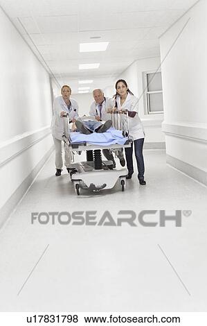 Doctors wheeling patient down hallway View Large Photo Image Stock Photo - Doctors wheeling patient down hallway. Fotosearch