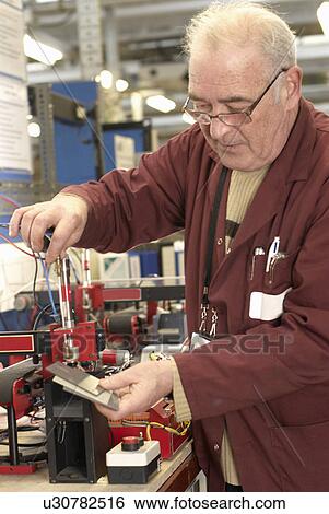 Stock Photograph - Electrical engineer working in shop. Fotosearch